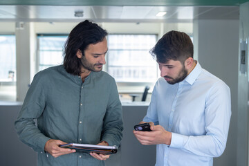 deux collègues, jeunes employés de bureau travaillent en équipe et discutent assis devant un ordinateur portable - 775758885
