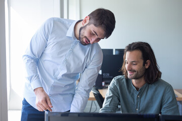 deux jeunes collègues et amis discutent en riant dans leur bureau