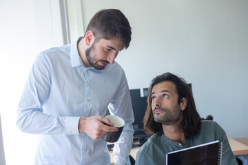 deux collègues, jeunes employés de bureau travaillent en équipe et discutent assis devant un ordinateur portable - 775759033