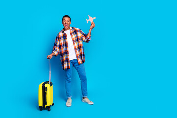 Full body portrait of nice young man suitcase small plane empty space wear shirt isolated on blue...
