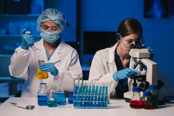 Team of biochemical research scientists working with a microscope for vaccine development in...