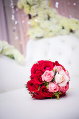 Wedding bouquet of the bride in red tones is on a white  chair. Flowers for wedding reception.