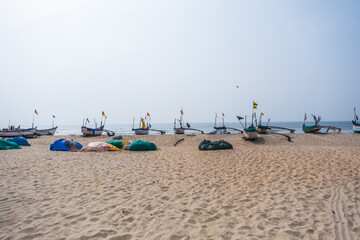 Fototapeta na wymiar old fishing boats in sand on ocean in India on blue sky background