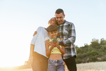 Beautiful girl with her parents holding a plant.