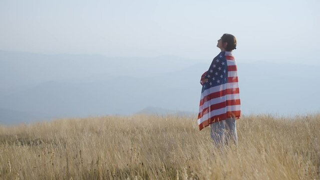 Woman with American flag on a Mountain peak.Pride and freedom concept