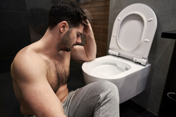 Sick man with stomachache next to the toilet - 775782077