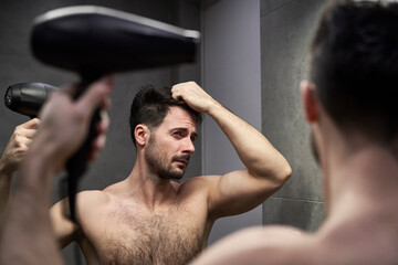 Caucasian man drying hair in the bathroom