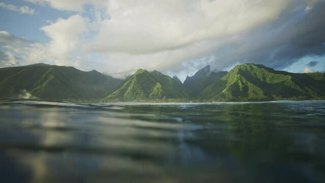 Tahitian island mountains reflect in ocean water, view from surface