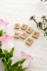 Scrabble letters dear mom on fresh table cloth with flowers