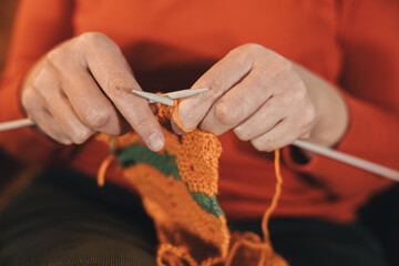 Close-up of the hands of an unrecognizable person knitting a sweater with two needles