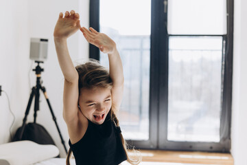 A sweet 6-year-old girl without 1 baby tooth stretches and smiles in the morning in a bright...