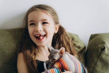 a sincere happy girl rejoices at the kitten she was given. The girl hugs and plays with a small and cute cat