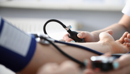 Close-up of persons hand on desk and doctor measuring blood pressure. Planned diagnostic. Modern...