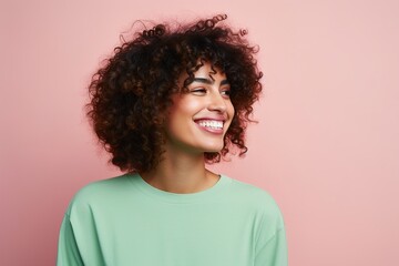 A woman with curly hair is smiling and wearing a green shirt