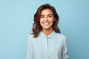A woman with a blue shirt and brown hair is smiling - Powered by Adobe
