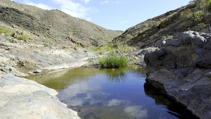 Canary Islands ravine with puddle of rainwater and mountains in the background. Climate change concepts