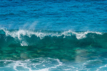 Front view of a crashing wave. Blue clear transparent water splash, ocean background.