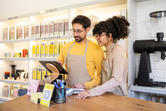 Cheerful multiethnic baristas using technology in a coffee shop