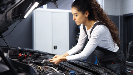 Young female automotive mechanic is working in her workshop