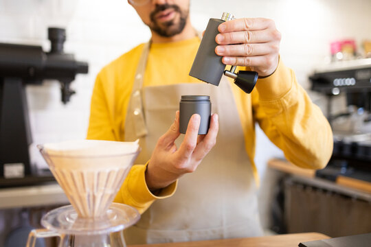Barista grinding coffee beans into a portable cup