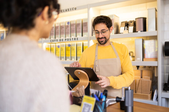 Friendly barista processing a mobile payment at a café