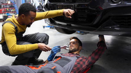 Two mechanics are working on repairing a car in a workshop