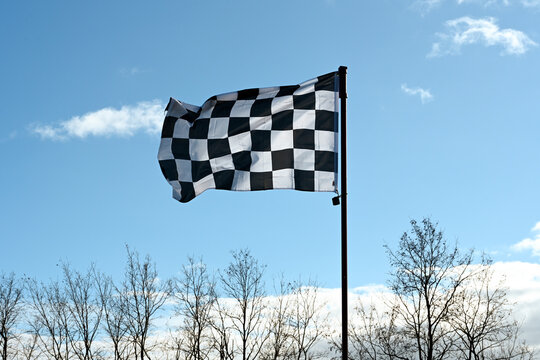 Drapeau &agrave; damier flottant sur fond de ciel bleu, au-dessus de la cime des arbres