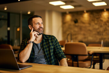 A businessman looking through the window, planning his next project while sitting at the office.