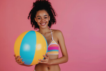 Funny young happy African American woman in swimsuit having fun holding inflatable ball and going...