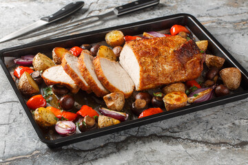 Healthy baked glazed pork loin with vegetables and mushrooms close-up on a baking sheet on the table. Horizontal