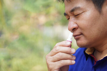 Asian man use menthol inhaler to smell for relief symptom of dizzy from hot weather condition. Concept, self first aid to protect from heat stroke. Refreshing. Aroma therapy.       - obrazy, fototapety, plakaty