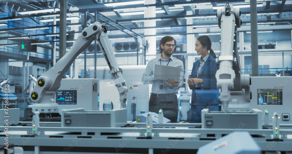 Fototapete Young Engineer and Asian Technician Having a Conversation and Using Laptop Computer. Specialists Monitoring, Analyzing Conditions at a Modern Electronics Factory with Automated Assembly Line