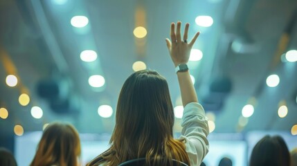 Confident businesswoman raising hand to ask question during seminar in conference hall.