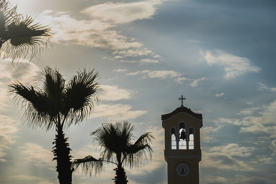 Palm trees and church tower with a bell in Athens.