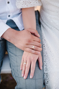 Engagement. Bride and groom hold hands with rings and sit at ceremony. Closeup. Details of wedding moments. Newlyweds together. Bride and groom outdoors. Top view. Couple hands.