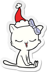 hand drawn sticker cartoon of a cat with bow on head wearing santa hat
