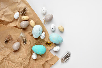 Easter eggs and feathers on a brown kraft paper background on a white table. Top view. For easter greeting cards with copy space. - 775862235