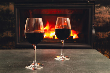 Two glasses of wine near the fireplace in the evening. Cozy evening by the fire