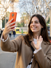 Young influencer woman doing a live show with a mobile phone in a city. Video call concept