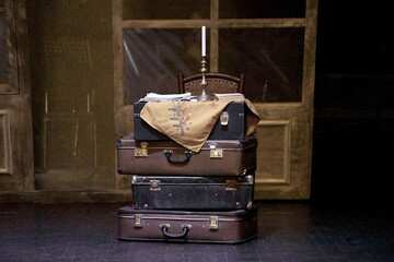 bunch of suitcases on a theater stage with candles in a candlestick .