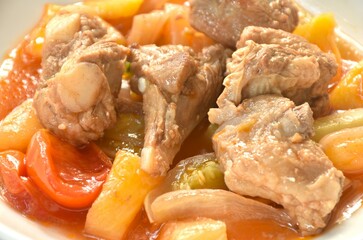 fried mixed vegetable with chop pork bone in sweet and sour gravy sauce on white plate 