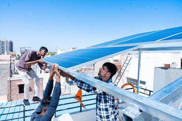 Indian workers installing solar panels on roof of house. Maintenance of photovoltaic panel system....