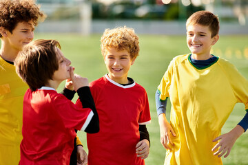 A group of energetic young boys in soccer uniforms stand together on the vibrant green soccer...
