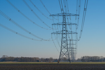 A row off electrical towers in the Dutch countryside. - obrazy, fototapety, plakaty