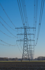 A row of electrical towers on a sunny day in the countryside.