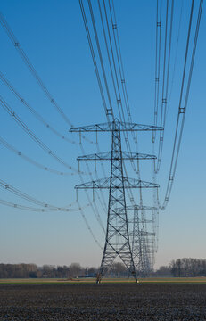 A row of electrical towers on a sunny day in the countryside.