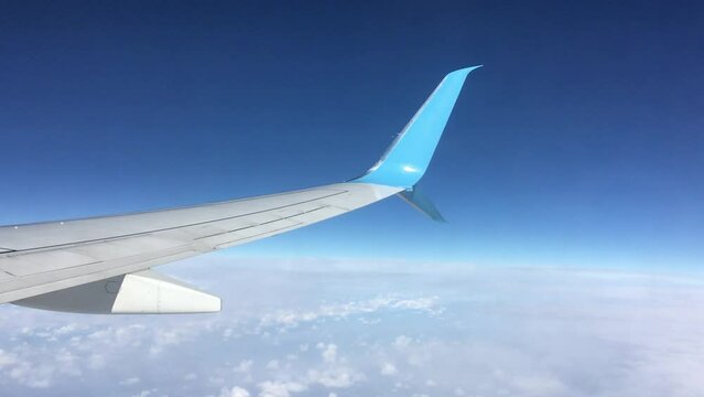 Passenger supersonic plane wing view from the flying aircraft high in the sky above white clouds