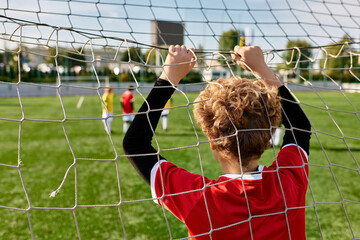 A young boy stands confidently in front of a soccer net, ready to defend against any incoming shots...