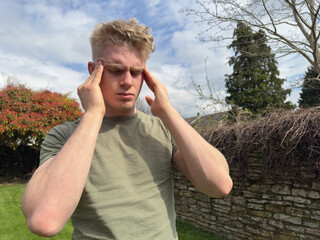Young handsome man having headache, rubbing his temples