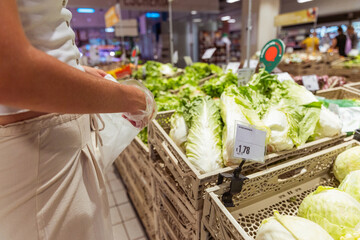 A woman is shopping for vegetables in a grocery store